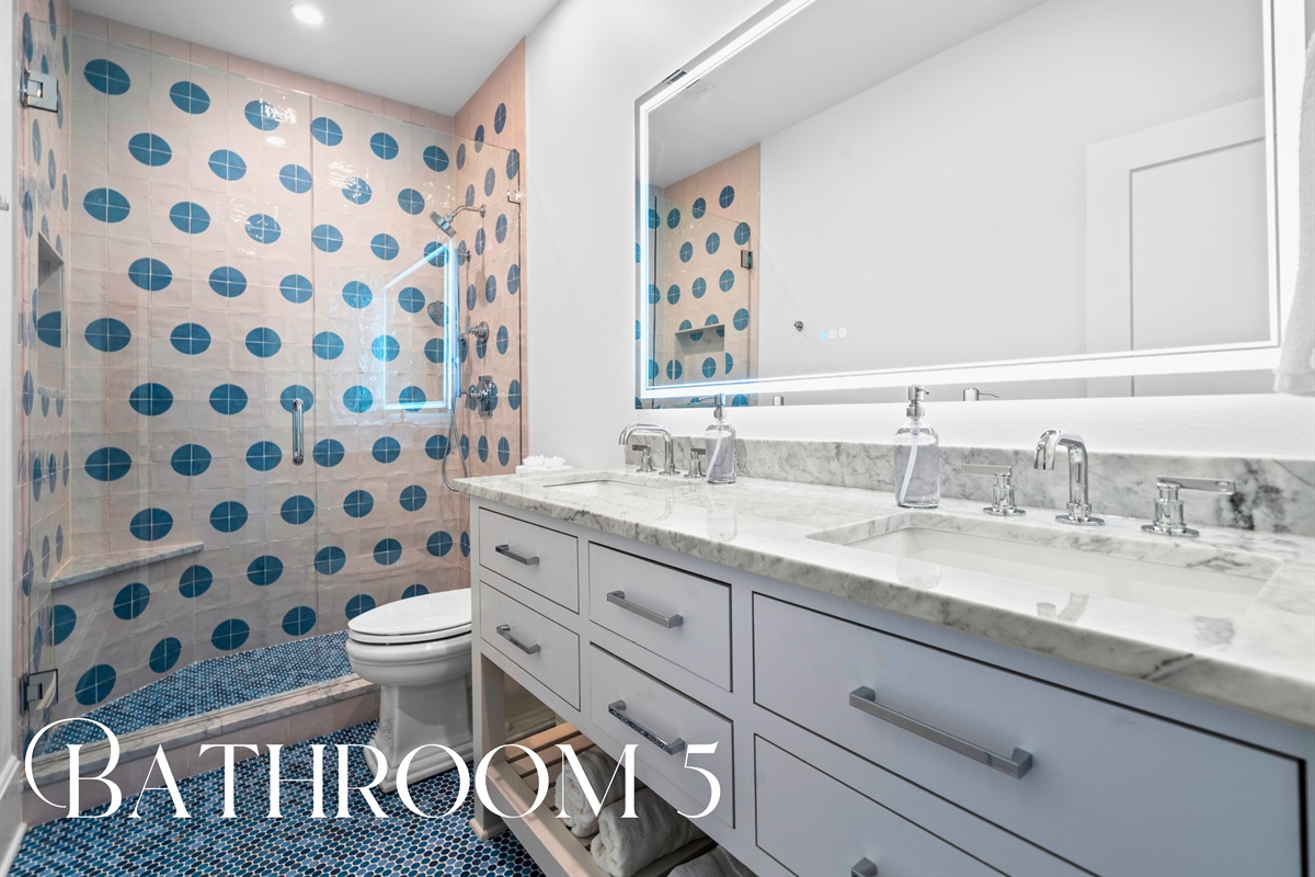 Bathroom with patterned tile and sleek white cabinetry.
