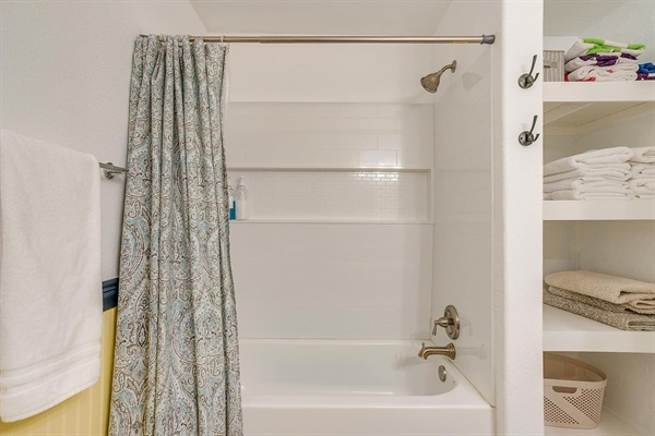 Full bathroom with shower/tub combo, fresh towels, and complimentary shampoo, conditioner, and body wash.