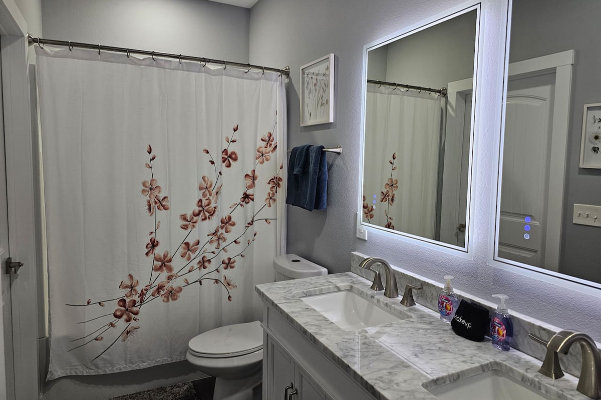Bright, updated bathroom with modern vanity and spacious shower/tub combo.