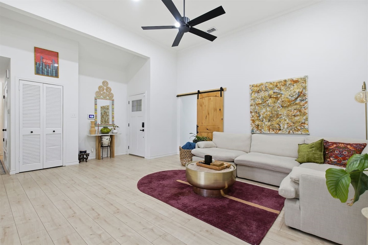 Modern Dallas living room with Smart TV, comfortable sectional seating, designer rug, ceiling fan, and seamless flow into dining and kitchen spaces.