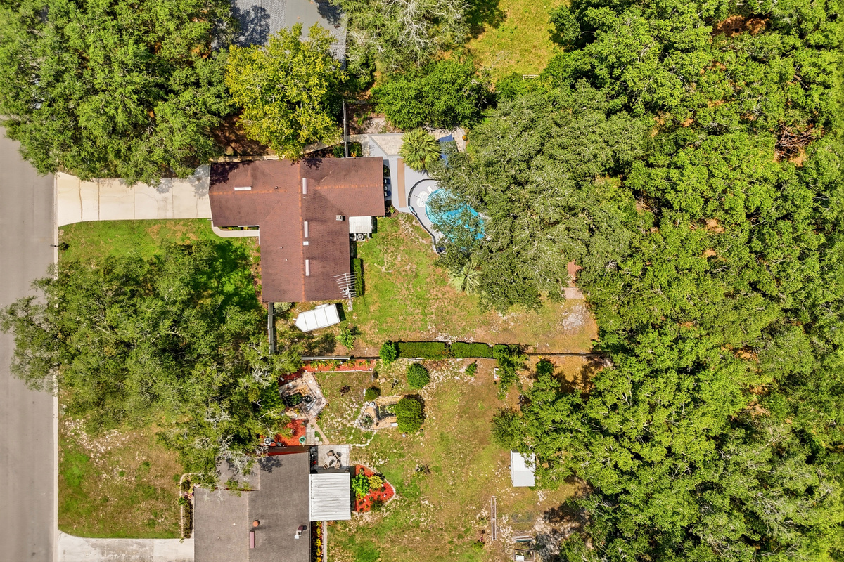 The property offers a generous lot surrounded by greenery, with the home, pool, and outdoor spaces tucked into a quiet natural setting.