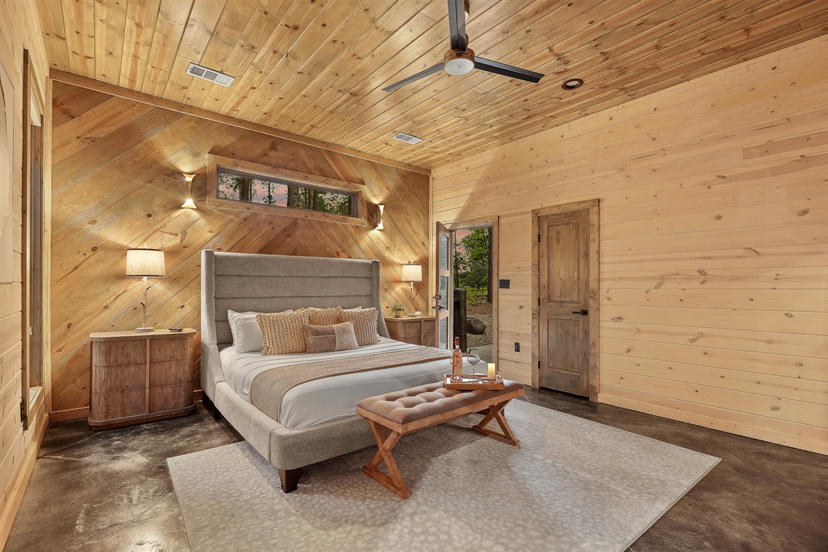 Unwind in this cozy king suite, where modern luxury meets rustic elegance. Enjoy plush bedding, warm lighting, and peaceful views through your private picture window &mdash; your own quiet retreat among the pines.
