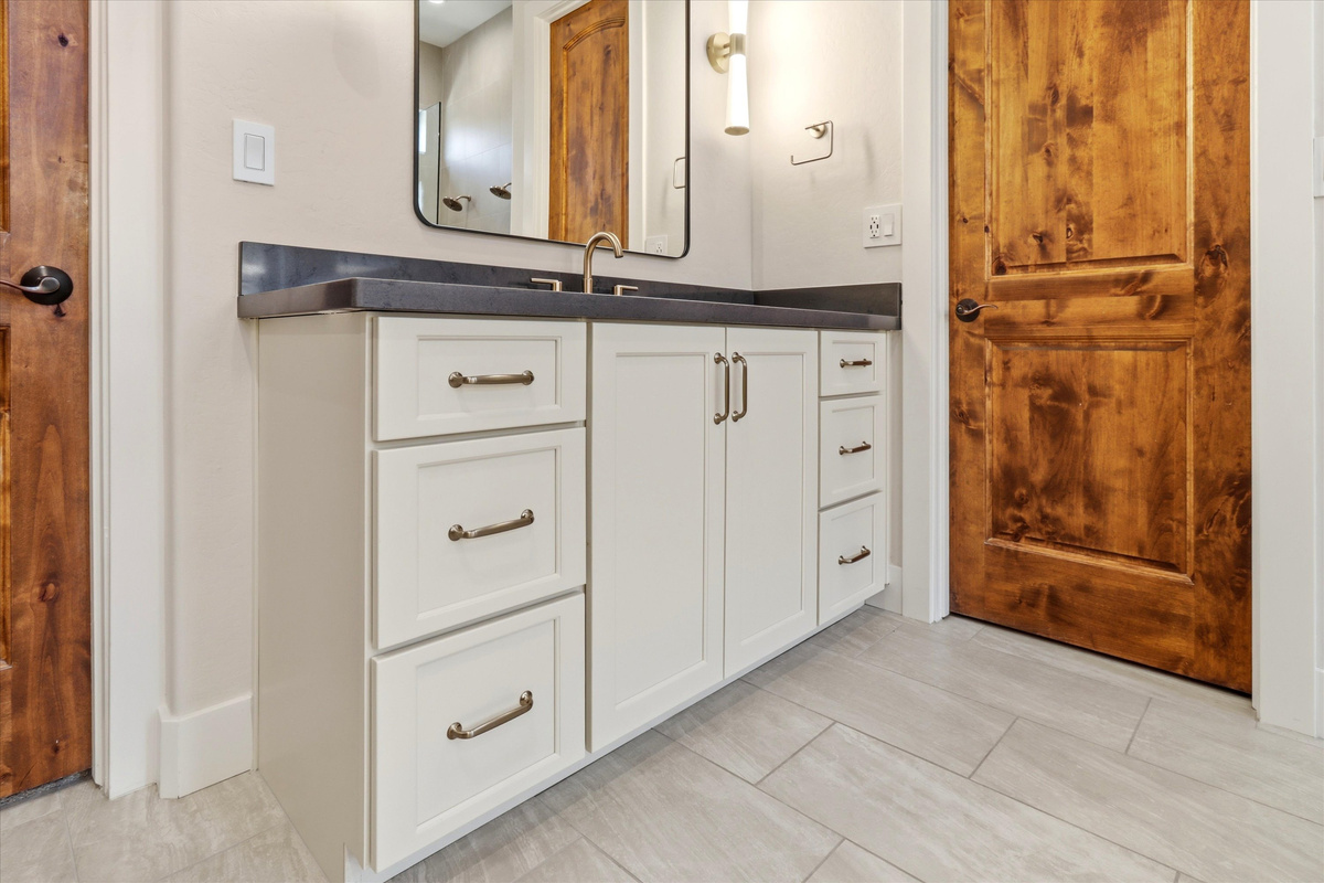 Bathroom vanity with cabinet storage, a clean counter, and warm wood doors nearby.
