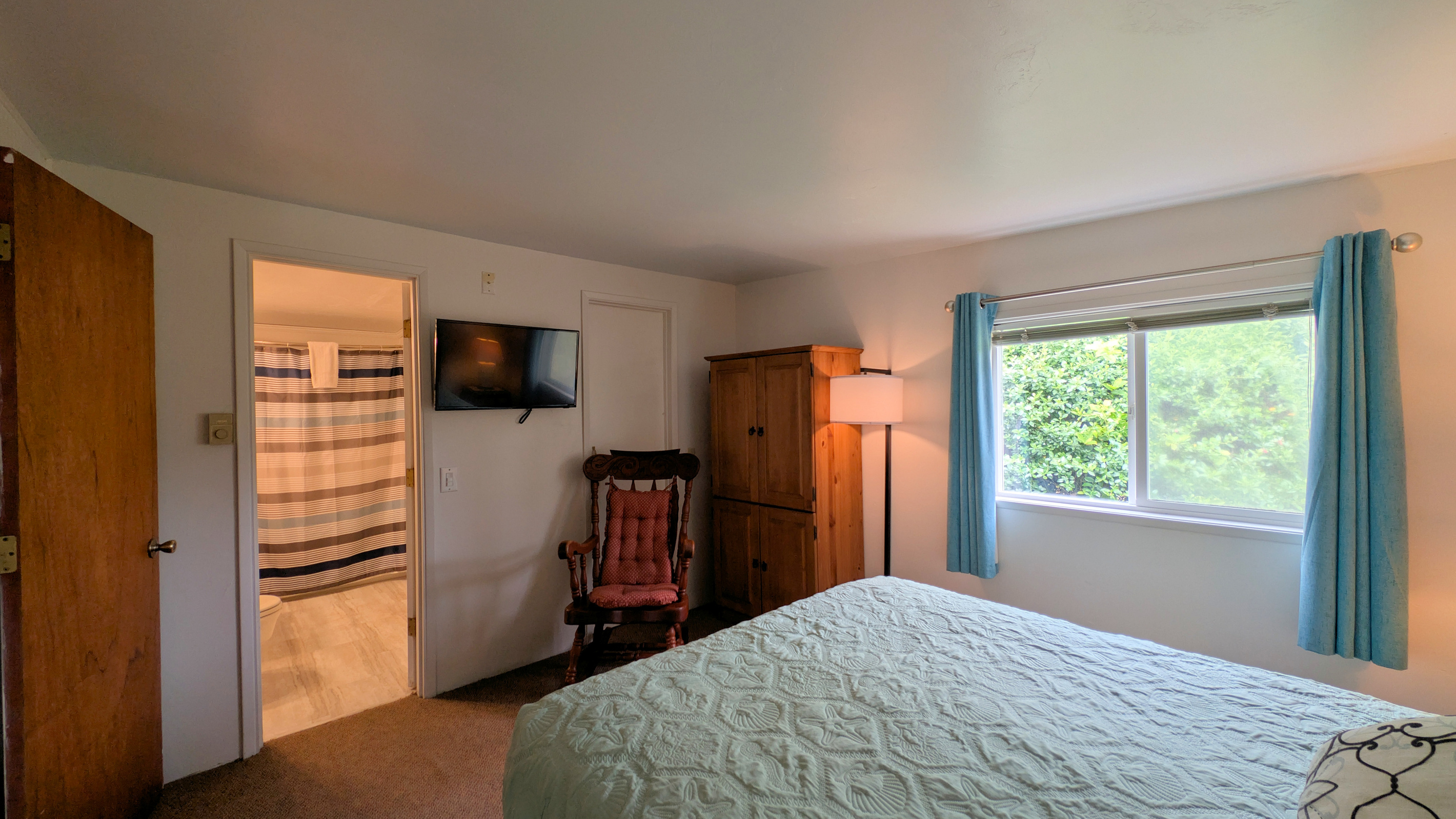 queen bedroom with TV, wardrobe & rocking chair.