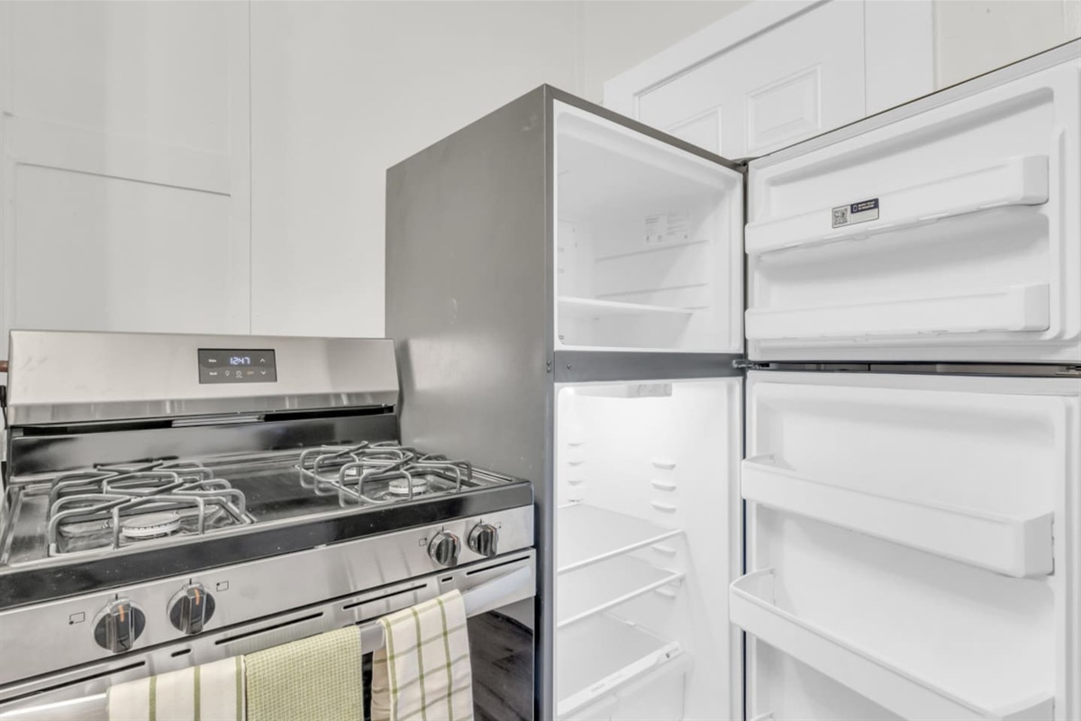Gas stainless steel stove and refrigerator interior with ample shelf storage.