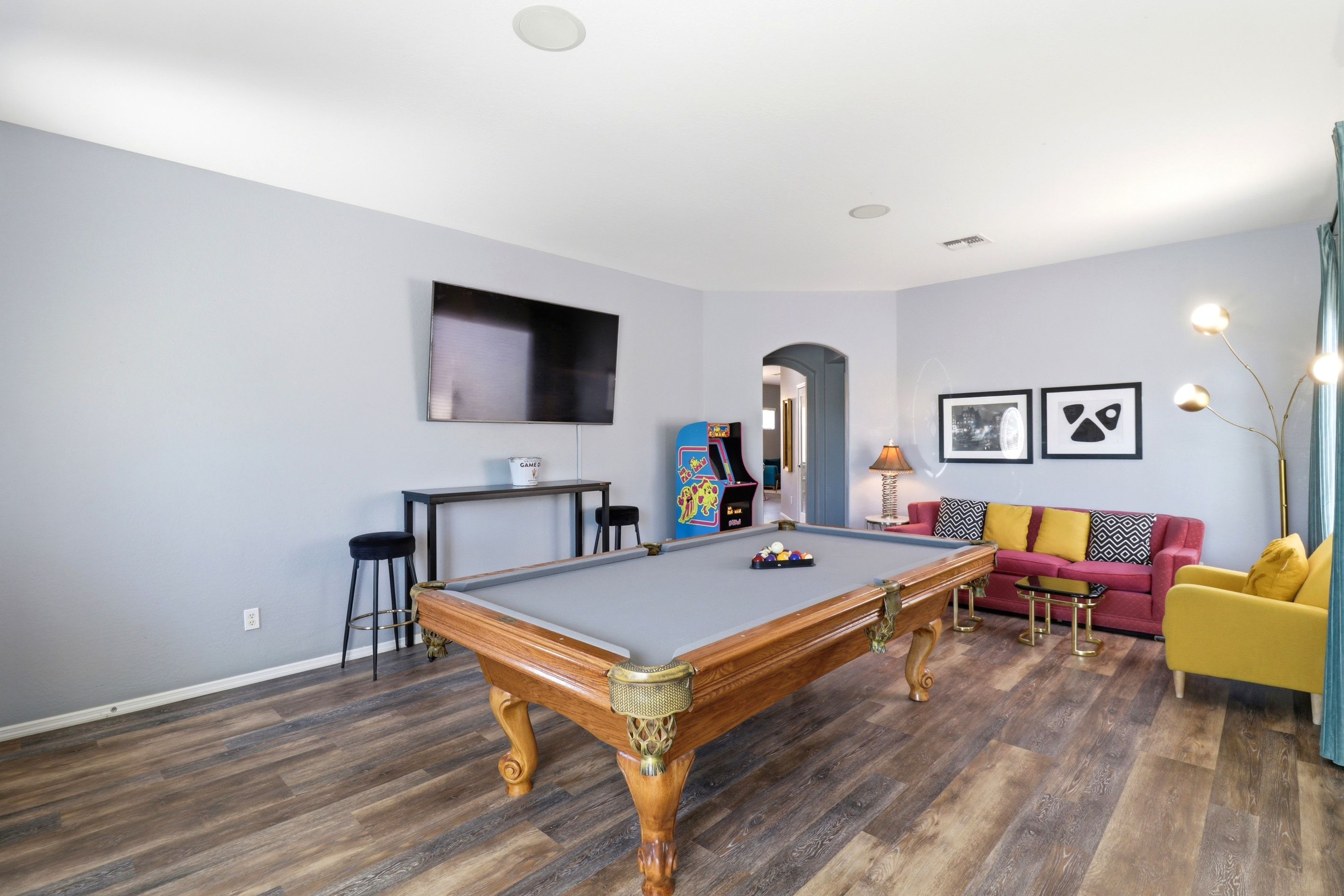 Game room with a pool table, arcade game, and seating for a fun night in.
