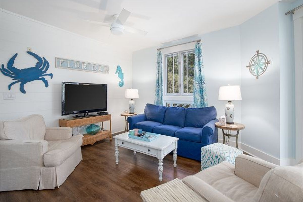 Living room seating area with HDTV, coastal wall art and a window to the resort gardens