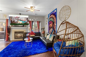 Spacious and eclectic living room with a cozy fireplace, comfortable seating, and a unique hanging chair. Perfect for relaxing and unwinding.