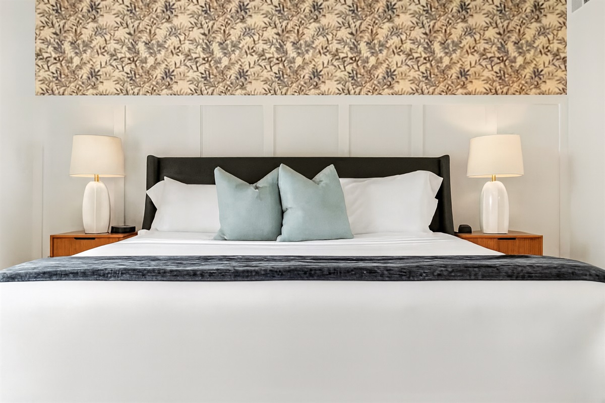 Rest easy in a plush king bed with stylish lighting, soft linens, and a relaxing atmosphere.