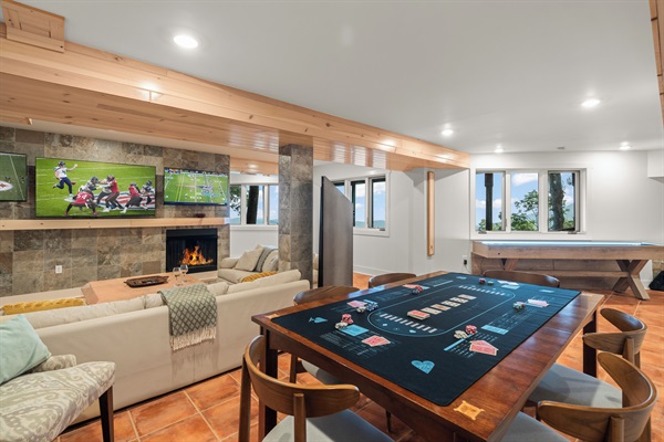 Downstairs rec room with multiple TVs, kitchenette, shuffeboard, and arcades