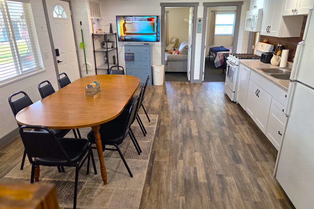 Kitchen has a large dining table to seat 8, TV, and storage racks.