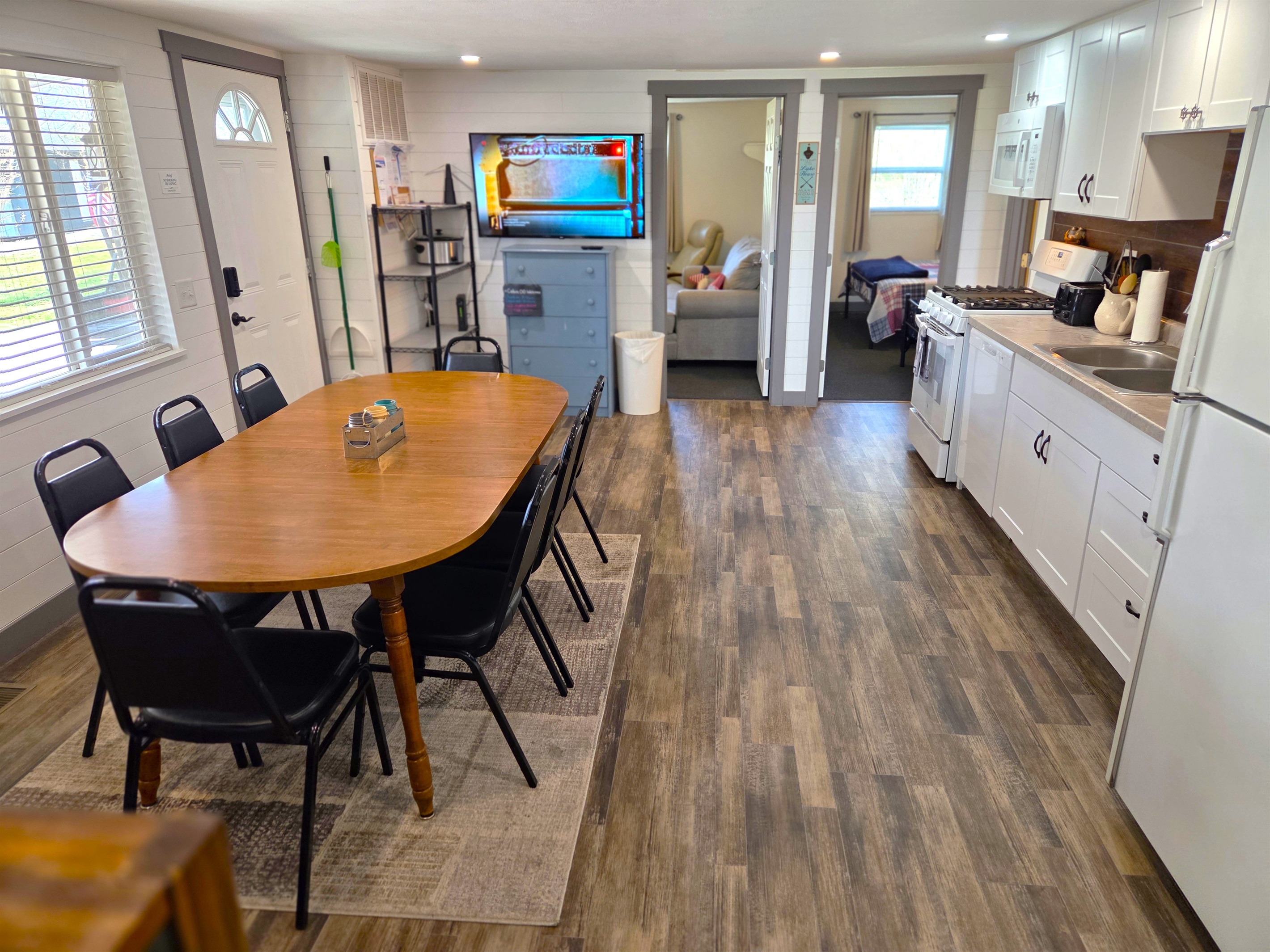 Kitchen has a large dining table to seat 8, TV, and storage racks.