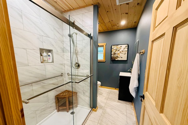 Bathroom with a spacious tile shower, bench, glass enclosure, and modern vanity. Bright, functional, and comfortable.