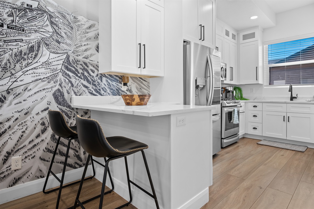 Gourmet kitchen with quartz counters, breakfast bar, and stainless-steel appliances.