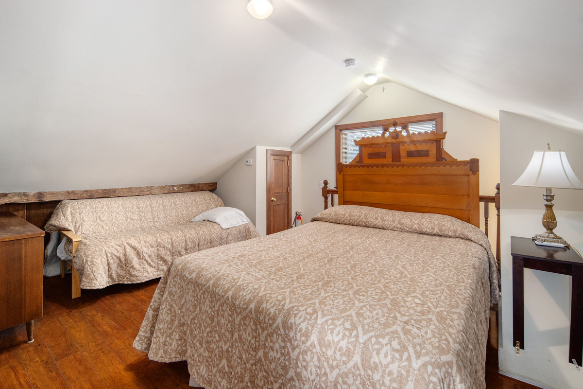 Vintage wood furnishings and exposed beams add character to the upstairs sleeping space.