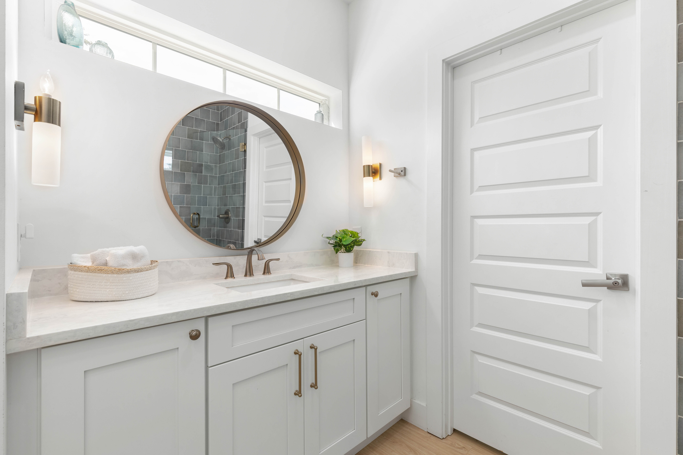 Marble counter, brass fixtures, and sconces to either side of the mirror. Small, calm and well finished - the sort of bathroom that makes getting ready for dinner feel like a part of the evening itself.