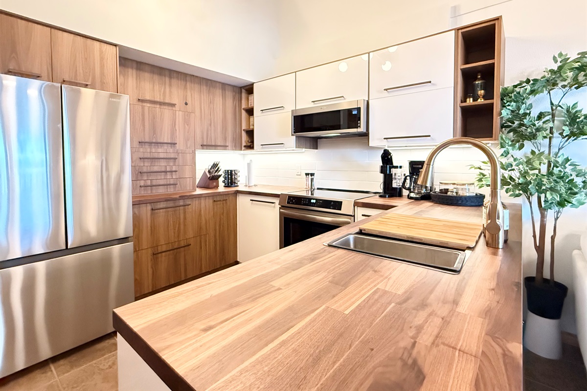 Ample Counter Space: This fully stocked kitchen provides plenty of counter space for meal preparation and a large wooden peninsula  perfect for gathering.