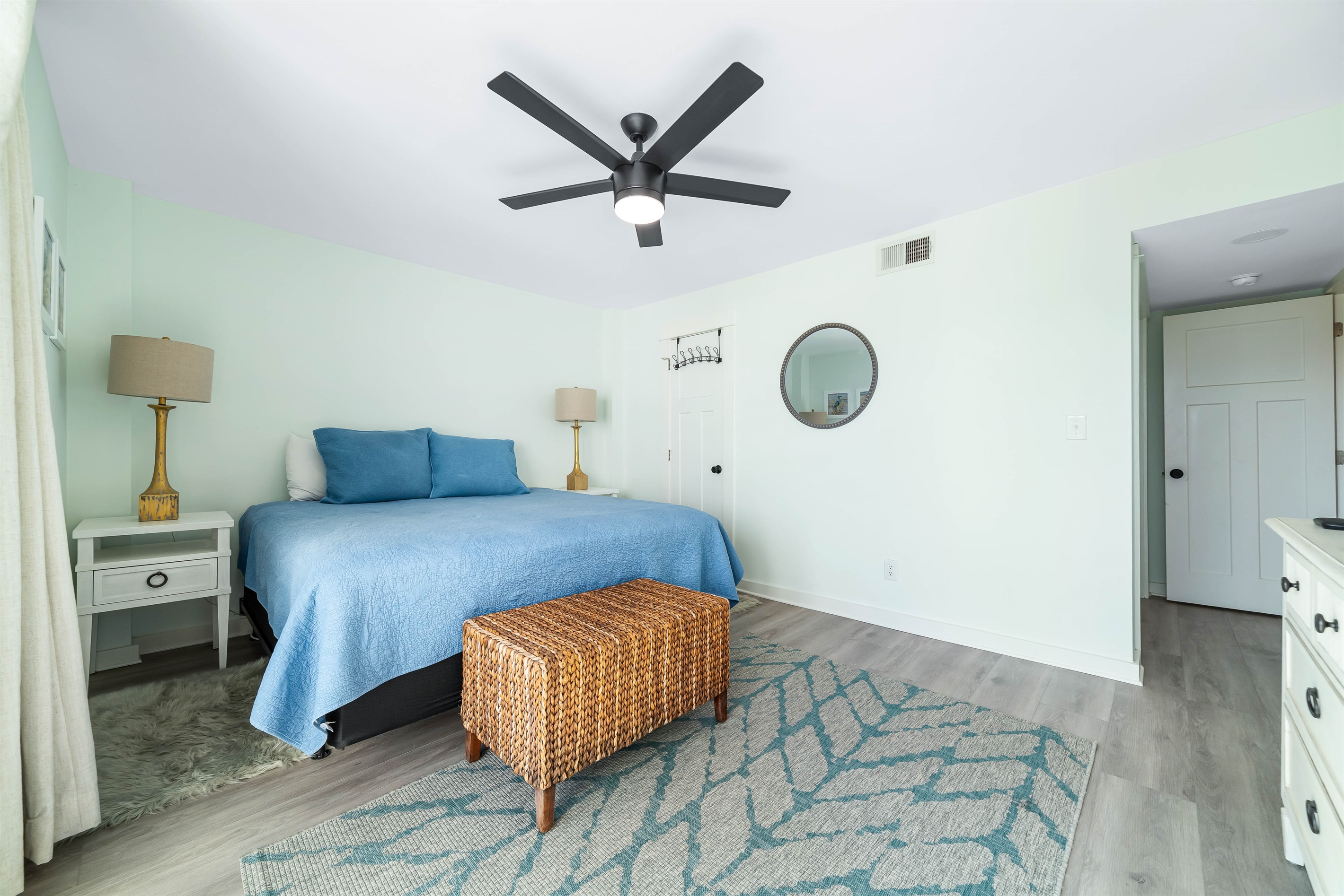 This charming bedroom offers a comfortable king-size bed with vibrant linens, complemented by matching nightstand with lamp, and practical storage solutions. A delightful space to unwind.