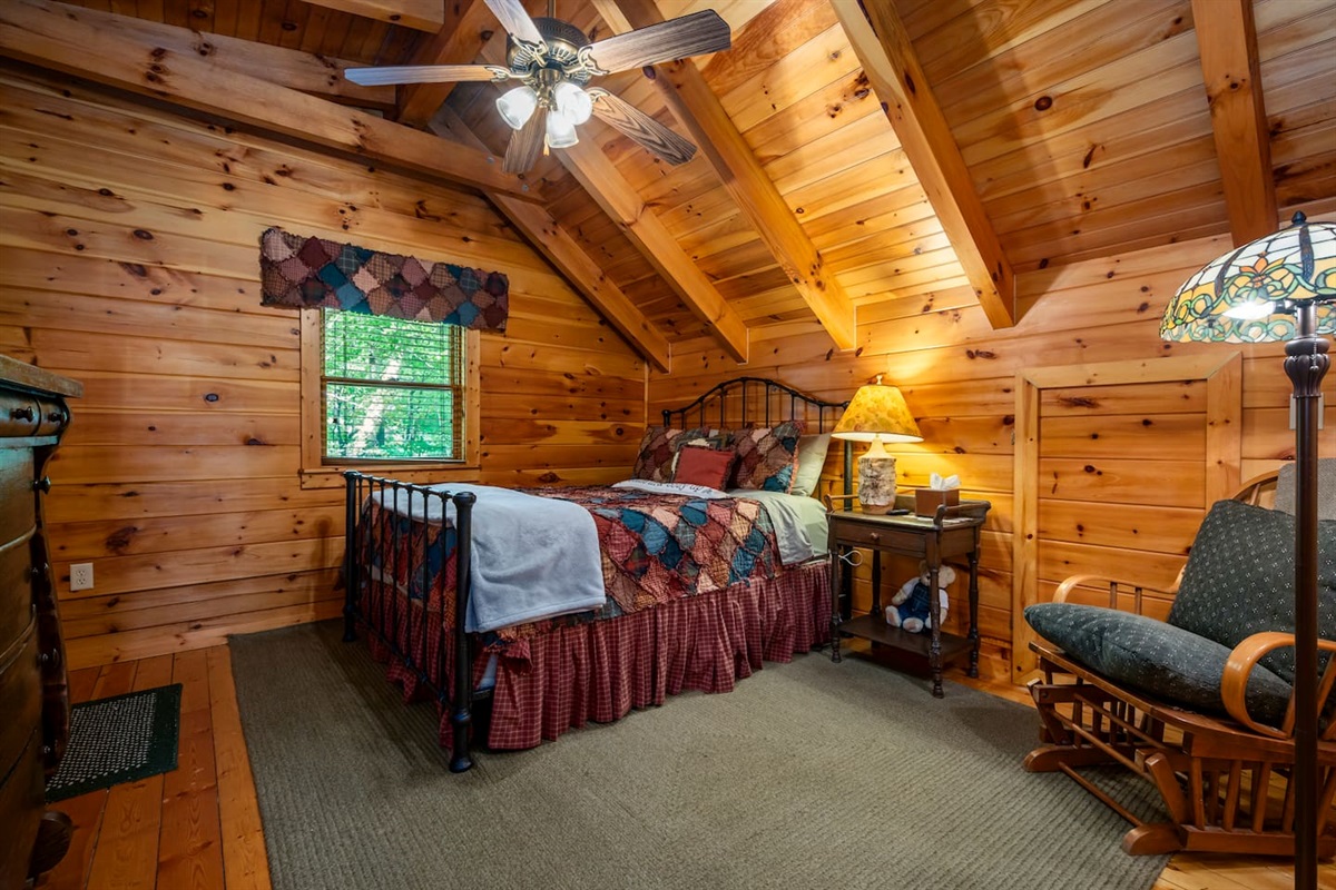 Charming loft-style bedroom tucked beneath vaulted wood ceilings, offering a cozy and peaceful cabin retreat. Rustic furnishings, warm lighting, and mountain decor create the perfect space to unwind and enjoy the mountains.