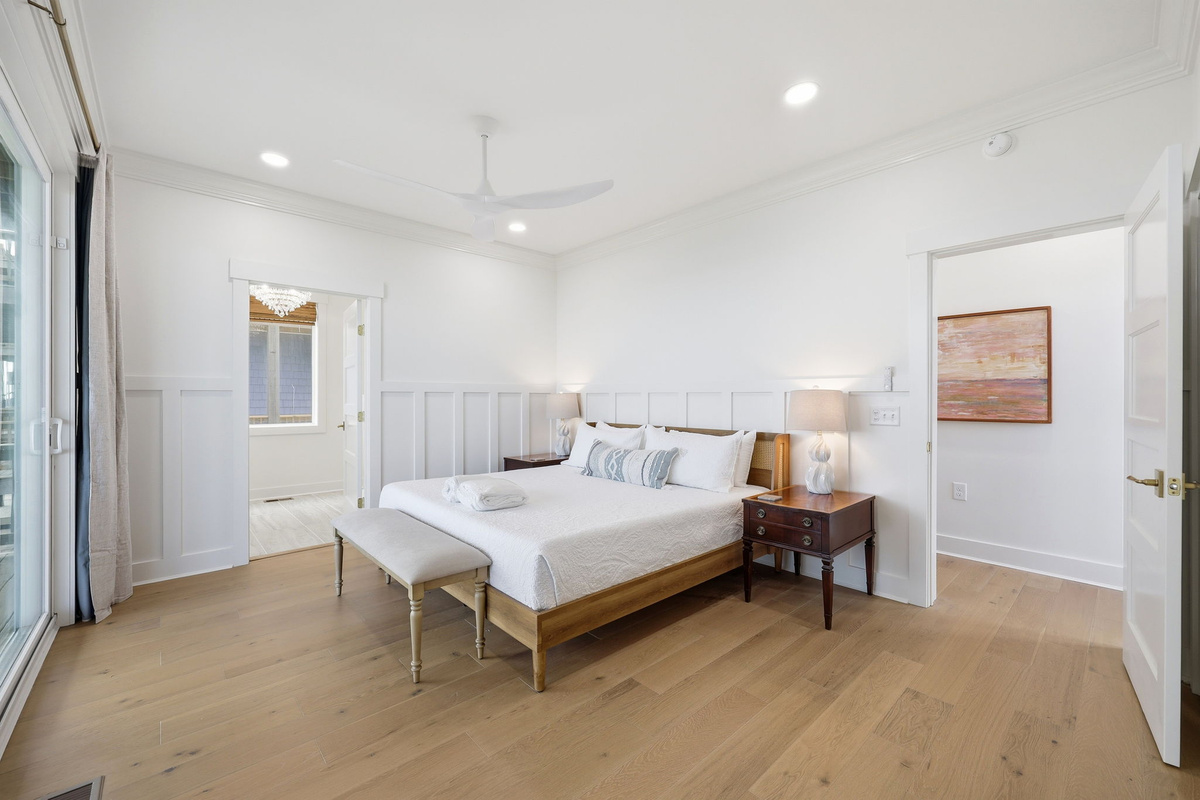 Second-floor king master bedroom featuring clean coastal design and ensuite entry