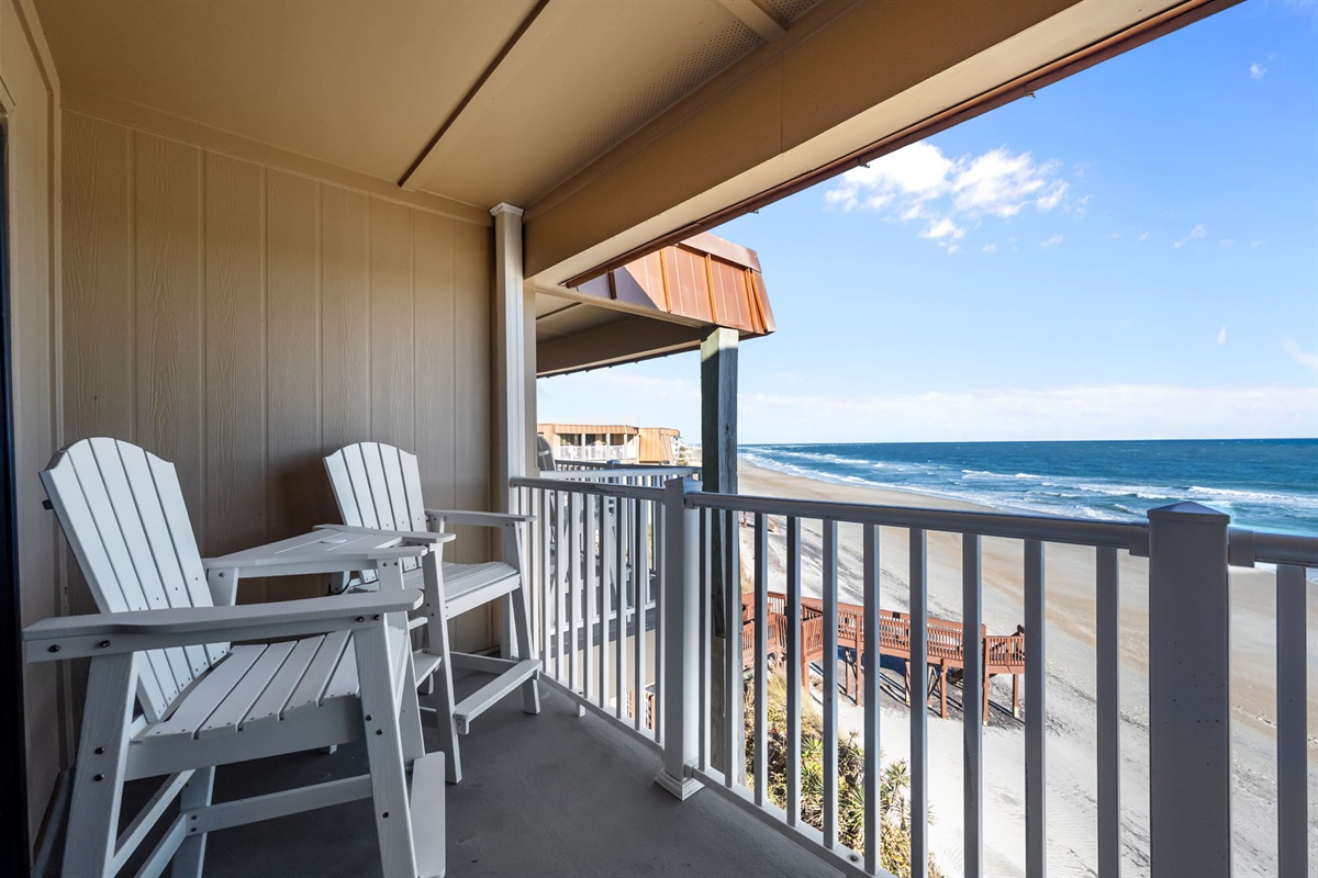 Private oceanfront balcony with Adirondack seating: front-row views of the shoreline and rolling waves