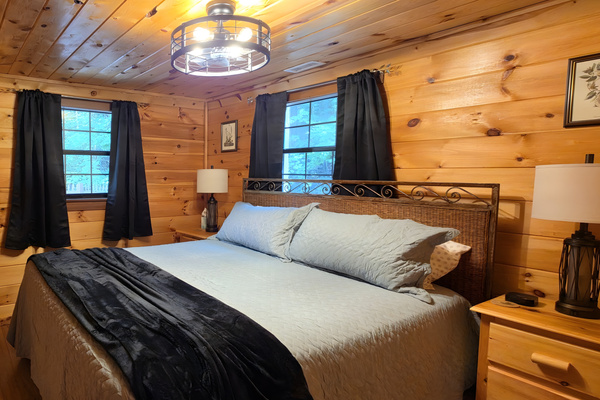 Retreat to this cozy, wood-paneled bedroom offering a comfortable king-size bed and a classic cabin atmosphere perfect for a restful night's sleep.  Bedroom 2 of 2 on lower level.