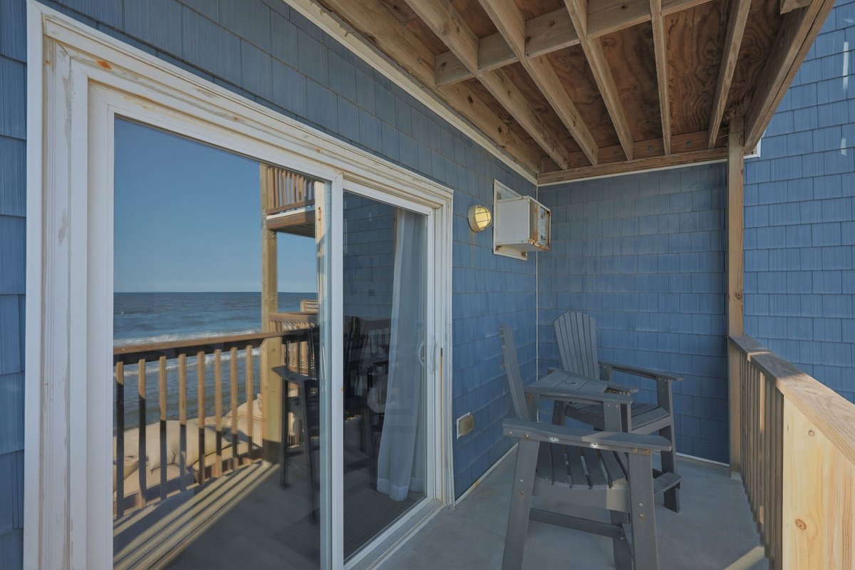 A private oceanfront retreat with outdoor chairs, a covered balcony, and easy access to the beach below