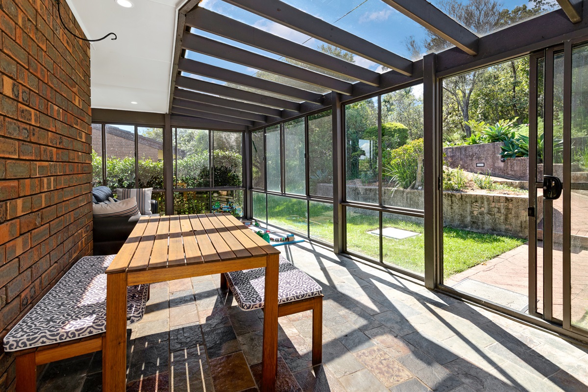 Sunlight pours through the glass roof and walls, making this sunroom one of the brightest garden-facing spaces at Bertie’s 3 beaches.
