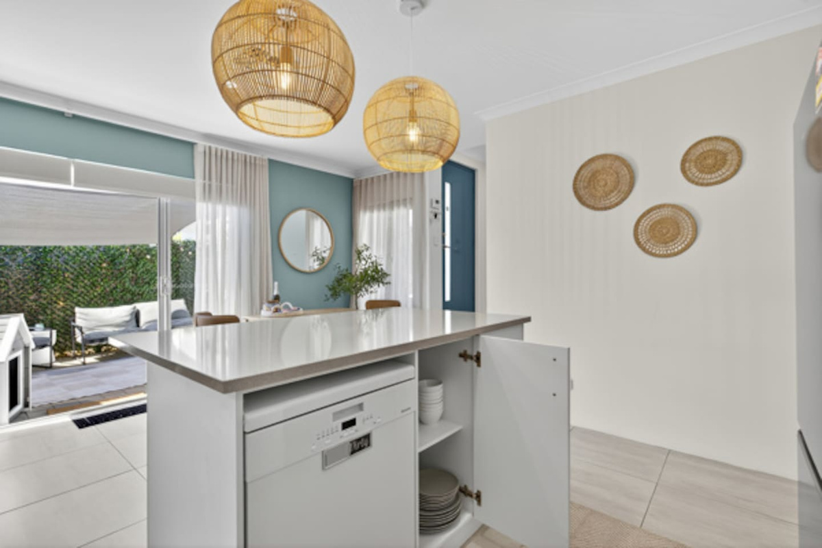 Kitchen island with dishwasher and crockery on hand, opening out through sliding doors to the private courtyard