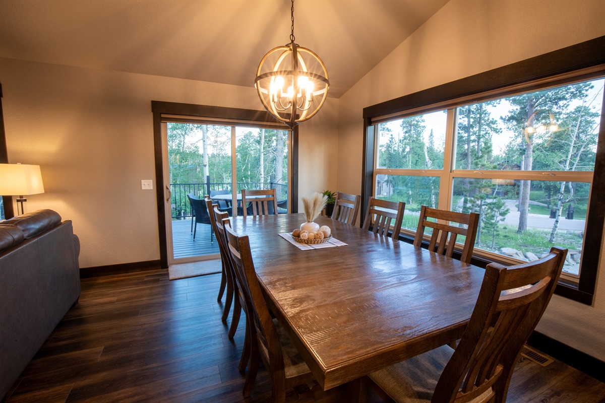 Enjoy a hearty meals at the rustic wooden dining table at "On The Rocks," illuminated by a stylish chandelier. Imagine stepping out to the deck through the sliding glass door to take in the forest views.