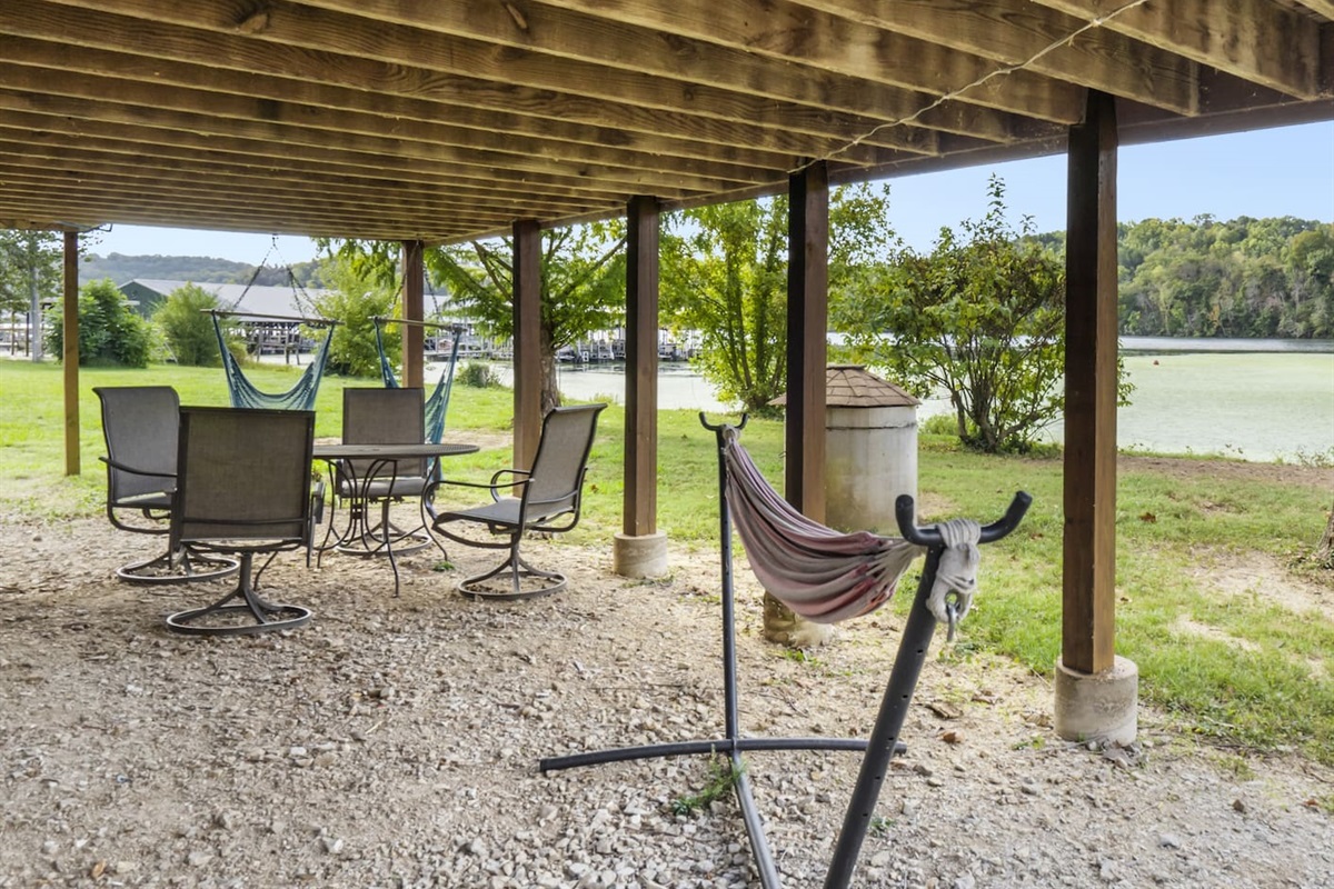 Downstairs patio with 2 hammock chairs, full hammock and dining area