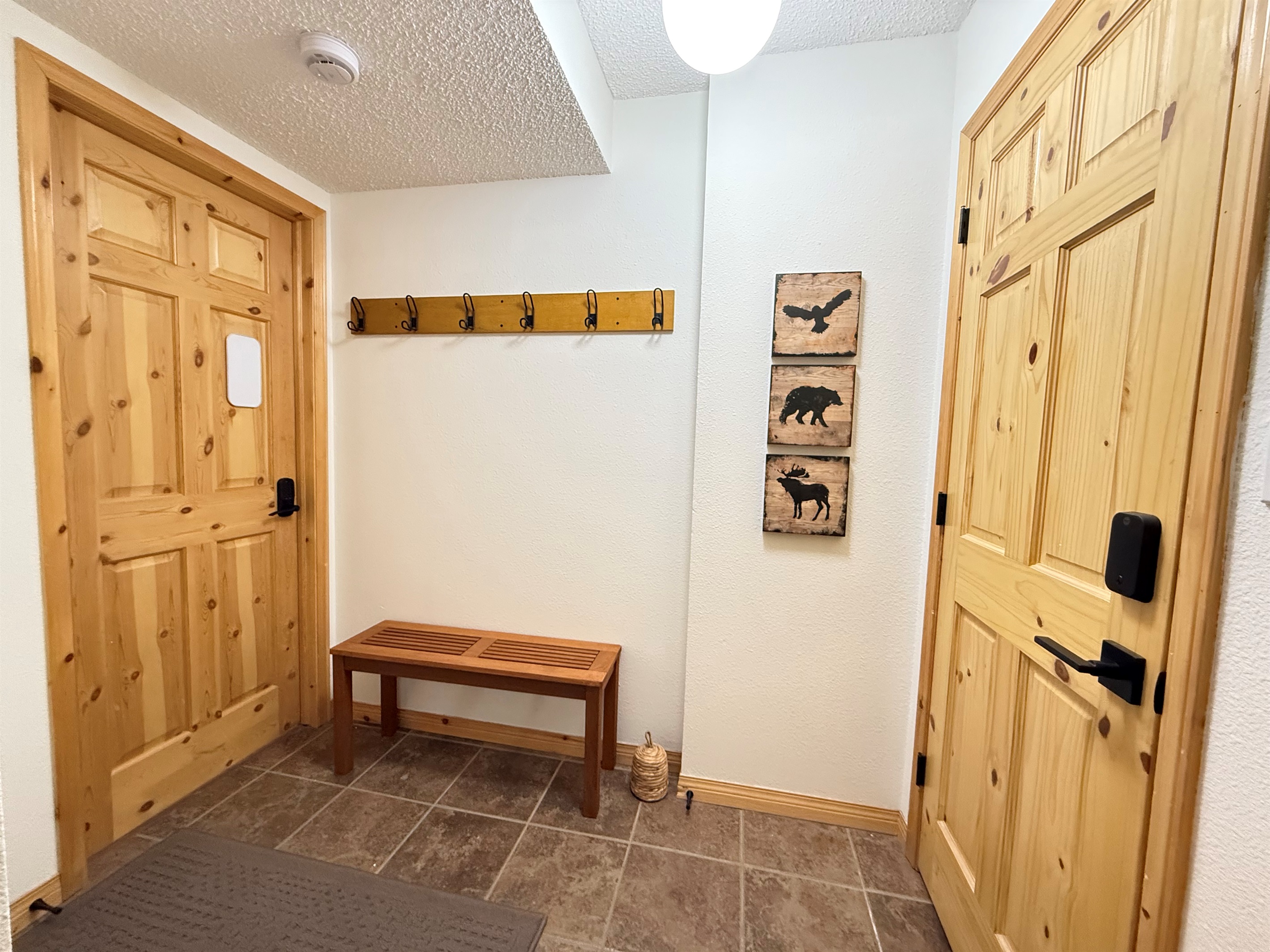 Efficient Entryway Storage: Compact and functional entrance at the Kimberley townhouse, featuring a wooden coat rack with ample hooks and floor space for boots. This entry is shared with the Bed & Bath suite (Left Door) and the Loft Suite (Right Door).