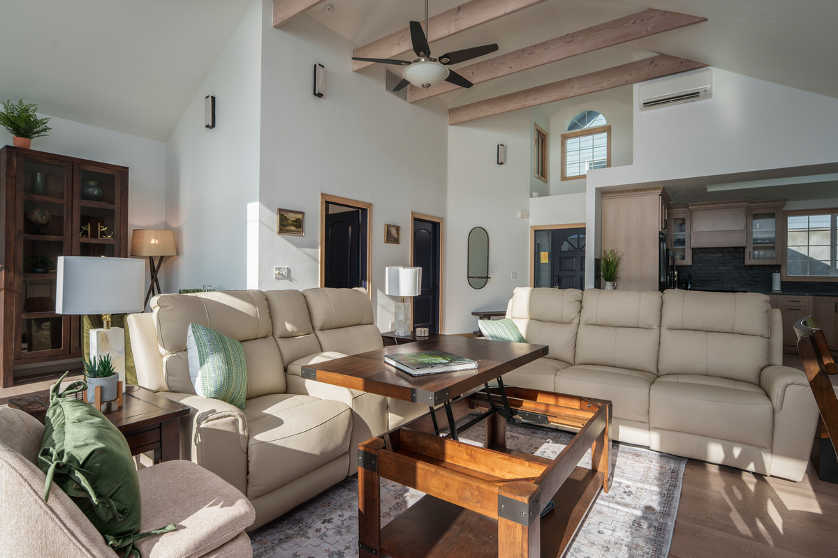 Bright, inviting living room with vaulted ceilings, exposed wood beams, comfortable seating, and plenty of space for the whole group to relax together. Coffee table converts into a laptop-friendly working station.