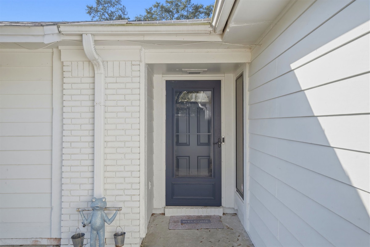 The front entrance offers a welcoming and sheltered entryway, highlighted by a stylish front door and clean white exterior. This cozy porch area provides a charming first impression as guests arrive at the home.