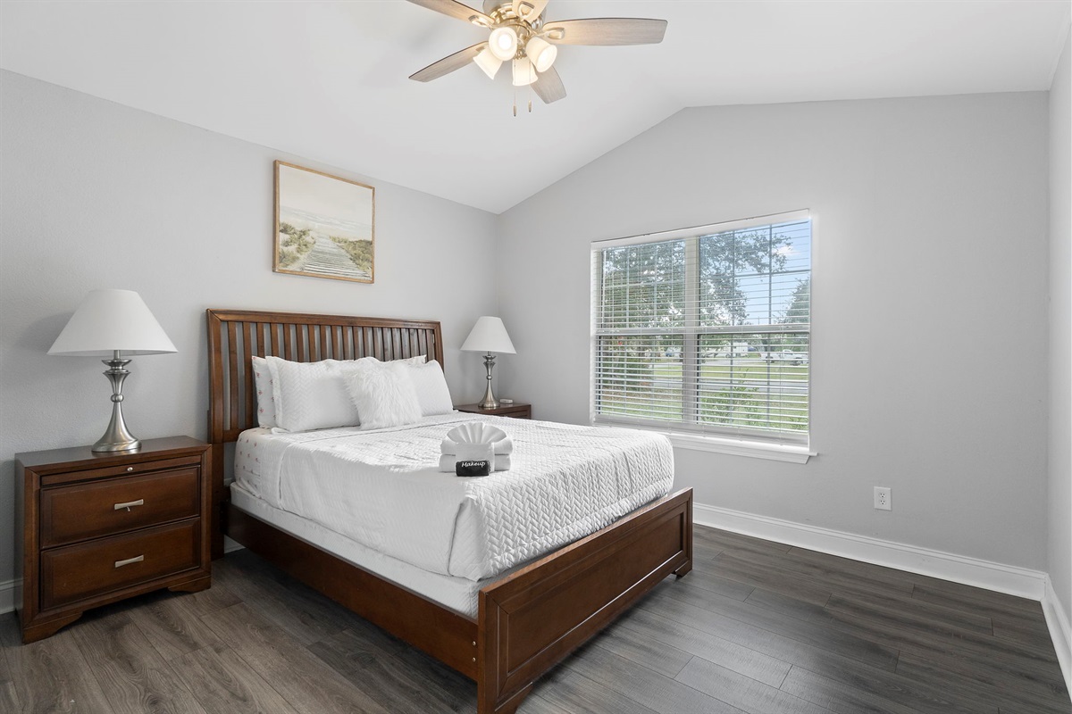 Enjoy a restful night's sleep in this beautifully designed bedroom, complete with a cozy queen bed, elegant wooden furnishings, and soft ambient lighting. The large window fills the space with natural light.