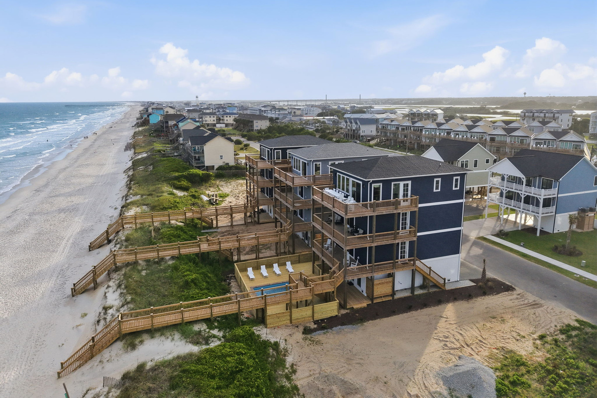 Aerial oceanfront overview showing the full home, private pool deck, and extensive elevated boardwalk system connecting directly to the beach