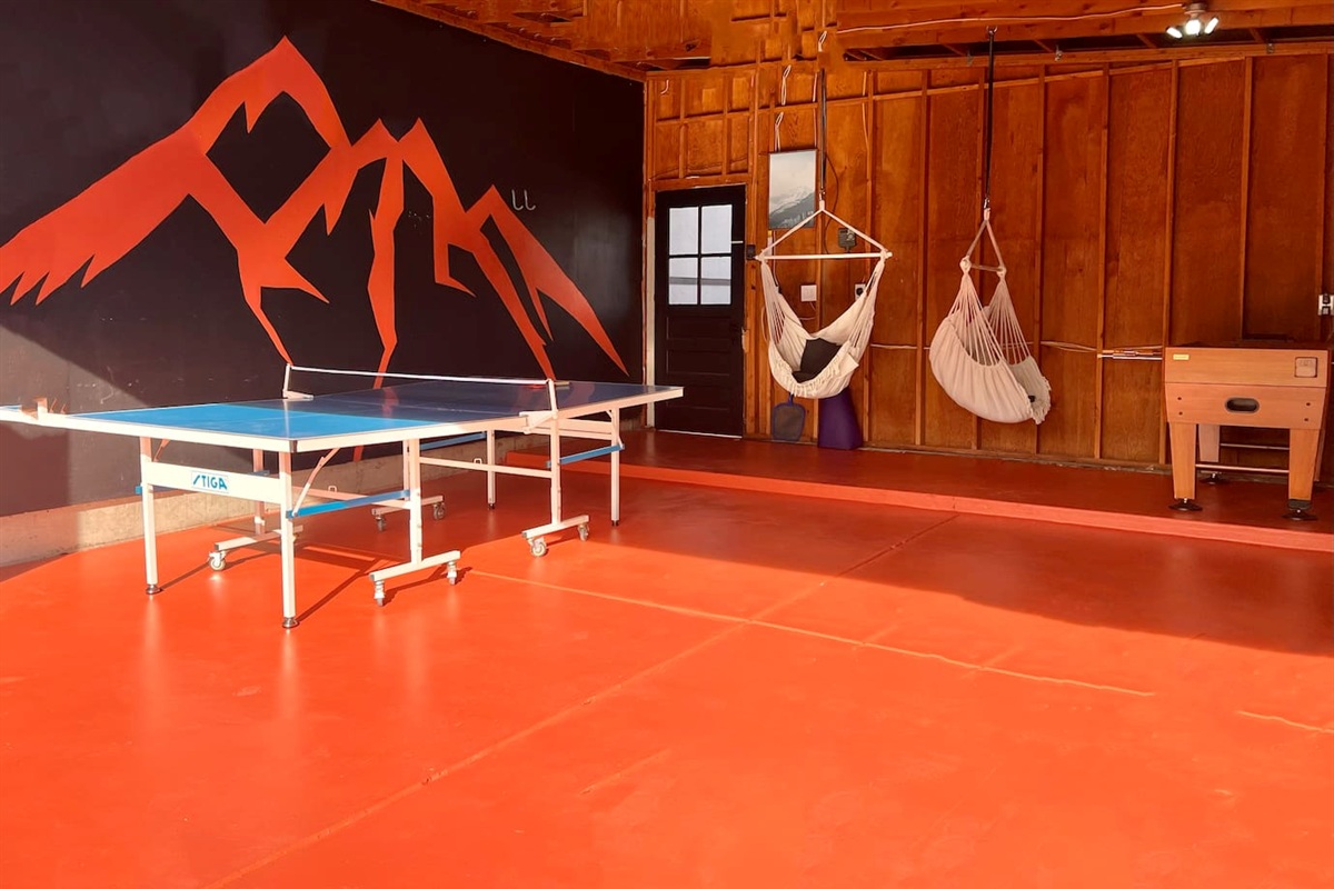 Converted garage for games with ping pong, foosball, hanging chairs and mountain mural for rain or shine entertainment. 
