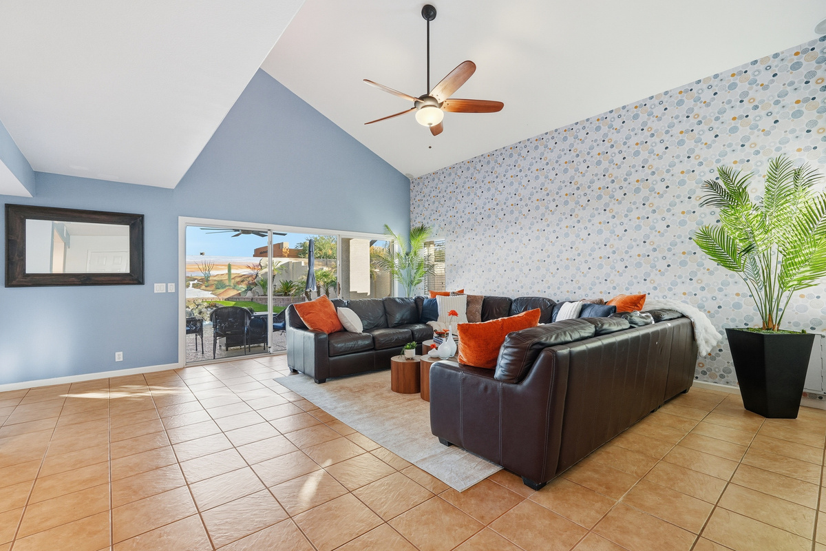 Living room with vaulted ceilings, large TV, sectional seating, and wide windows overlooking the pool 