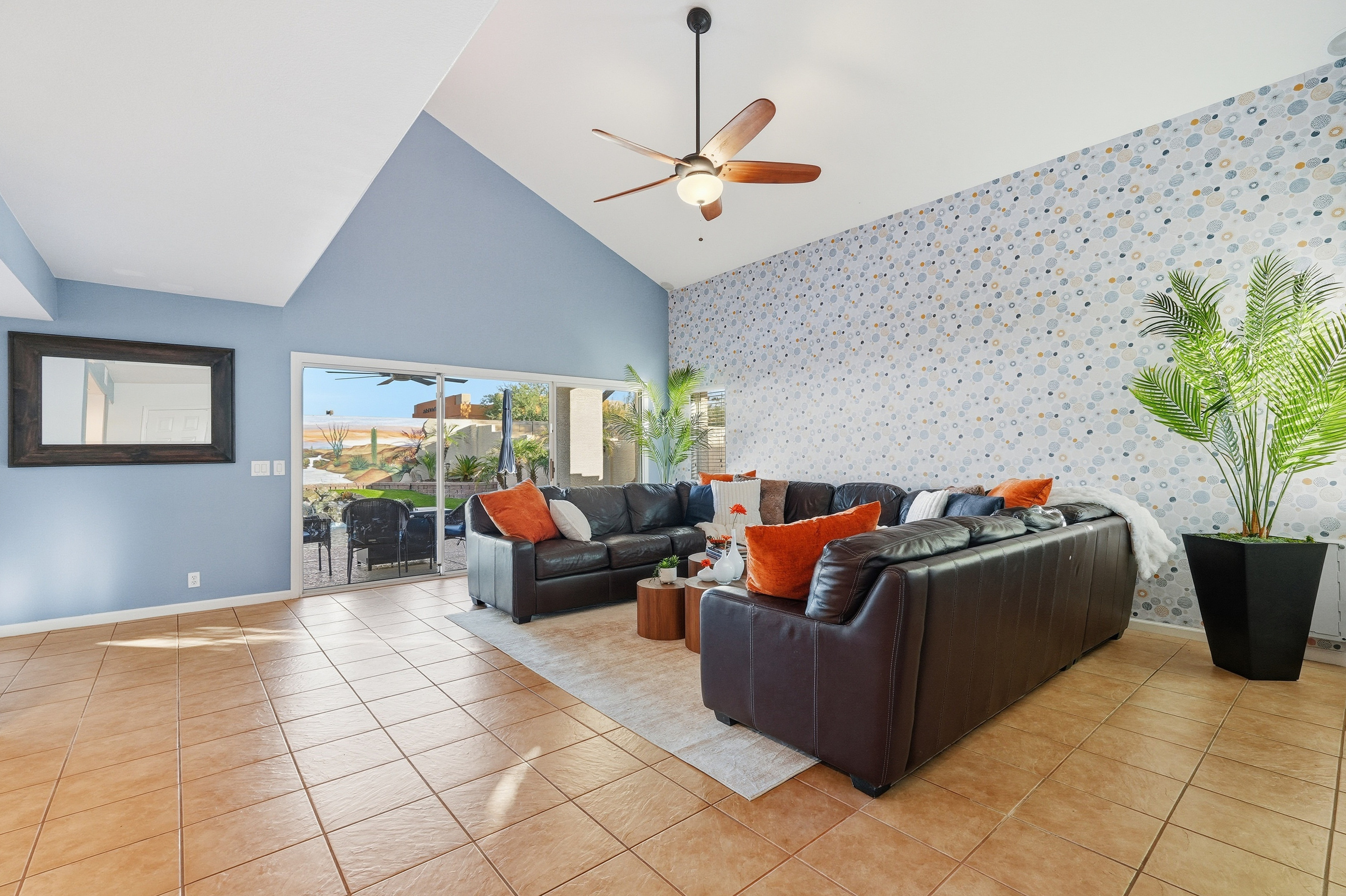 Living room with vaulted ceilings, large TV, sectional seating, and wide windows overlooking the pool 