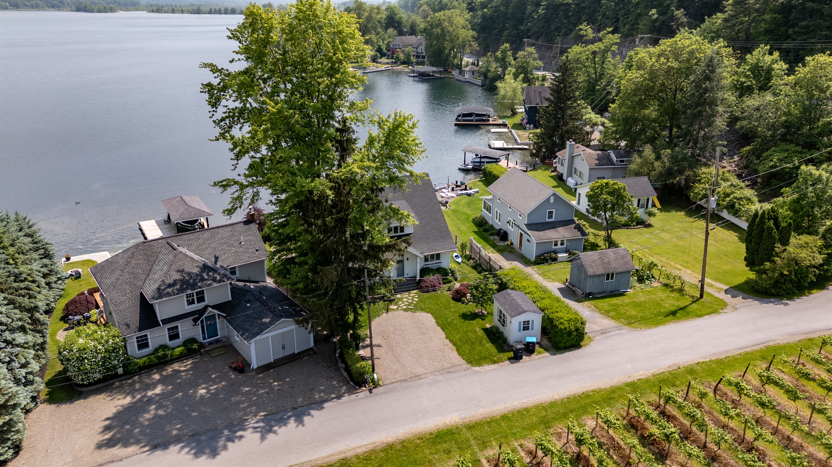 Stunning aerial view of a serene Finger Lakes waterfront retreat, complete with private dock, lush greenery, and charming lakefront homes—perfect for peaceful getaways and water adventures