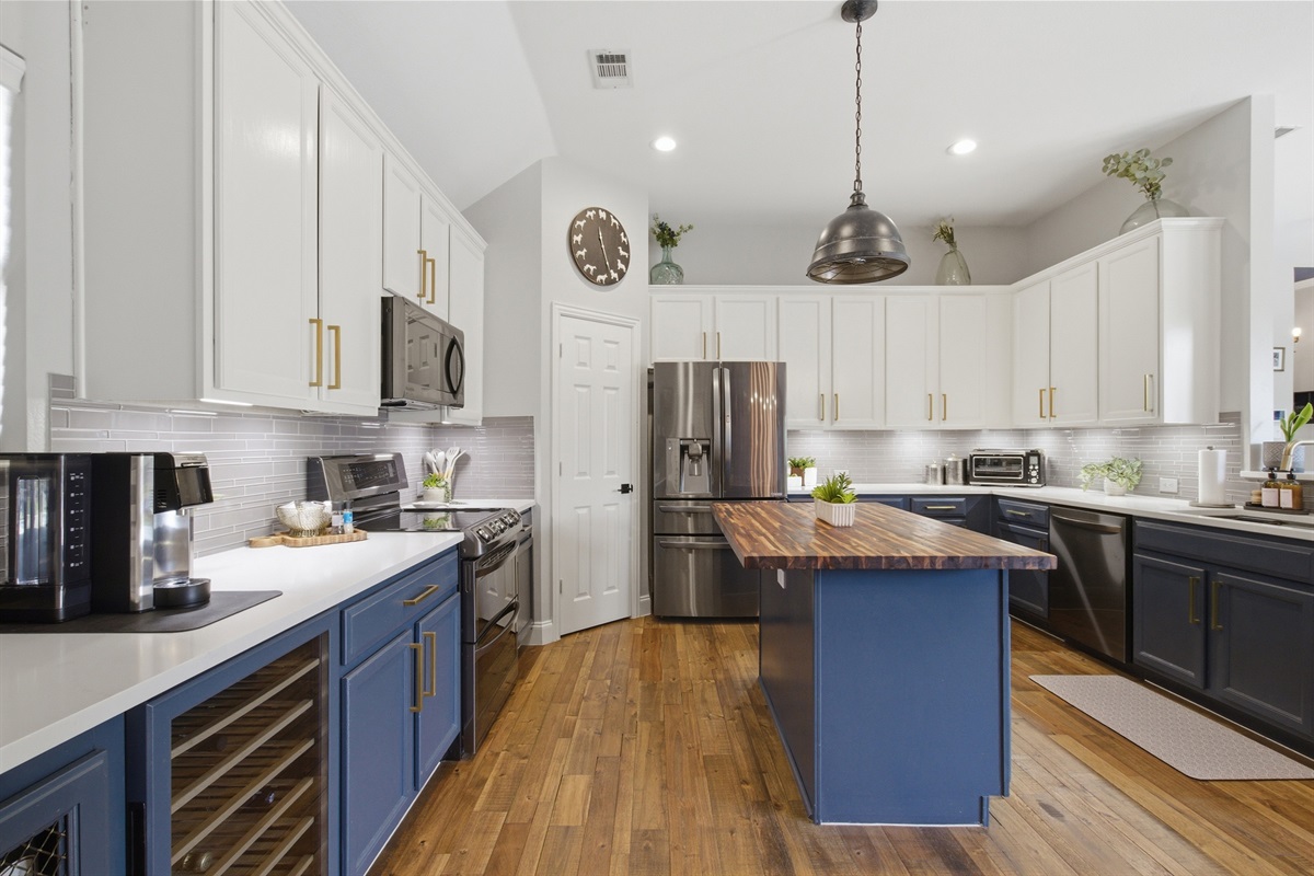 Fully equipped Kitchen with a large butcher-block Island, navy cabinetry, hardwood floors, and stainless steel appliances. Perfect for cooking up a Texas-sized meal.

