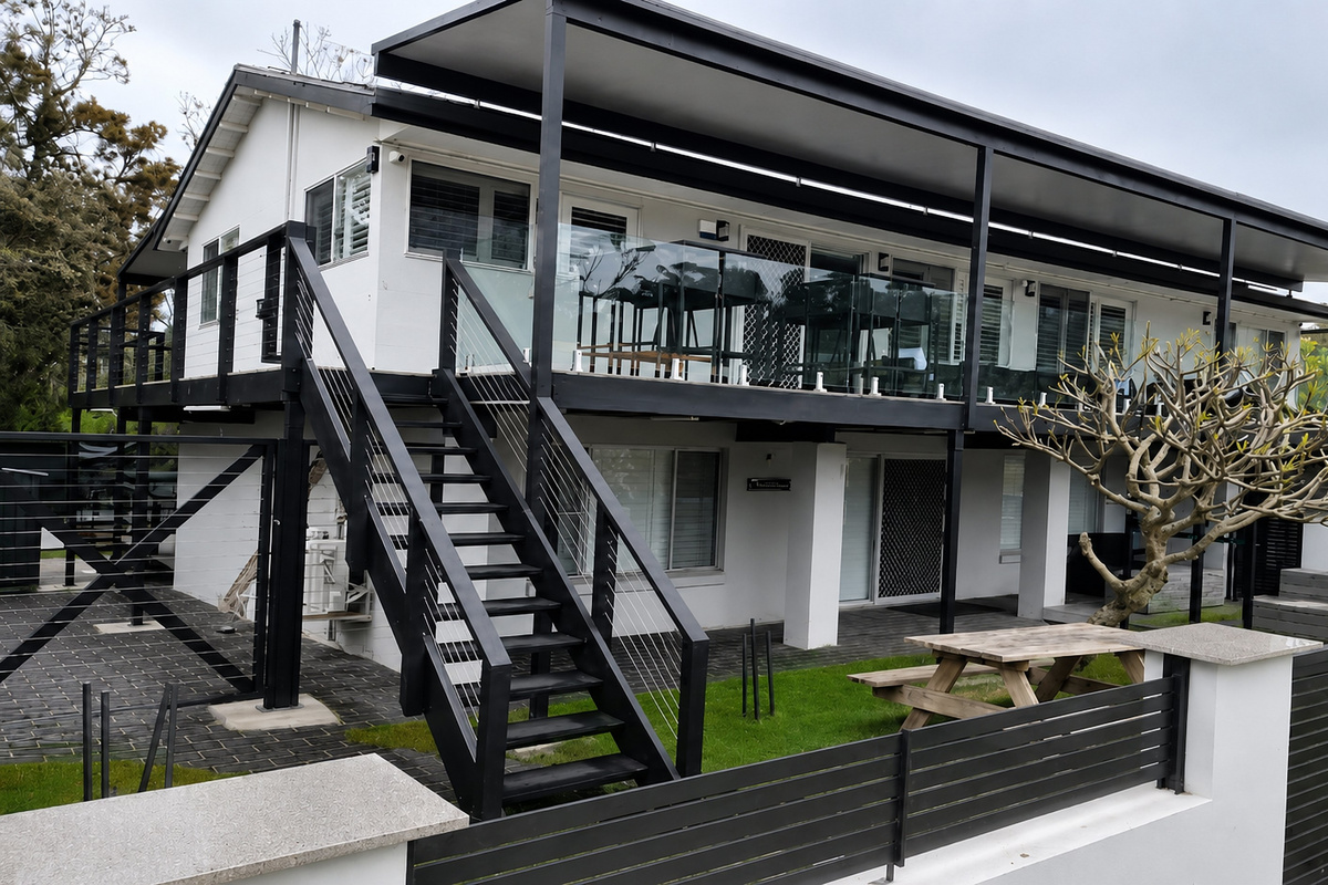 Skye’s Beach House Malua Bay from the side, with the upper balcony, outdoor stairs and large beach house layout in view.