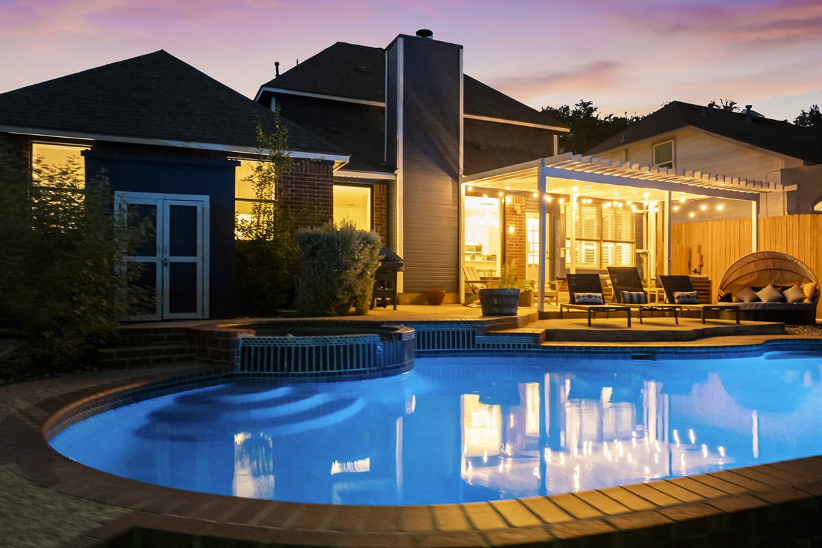 Stunning backyard retreat featuring a sparkling pool, spa, and a covered patio with cozy seating and string lights. Perfect for relaxing evenings or outdoor entertaining.