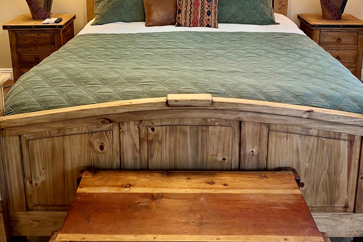 Unwind in the spacious bedroom, featuring a plush King-sized bed, a wall-mounted TV, and warm, rustic-style furnishings.