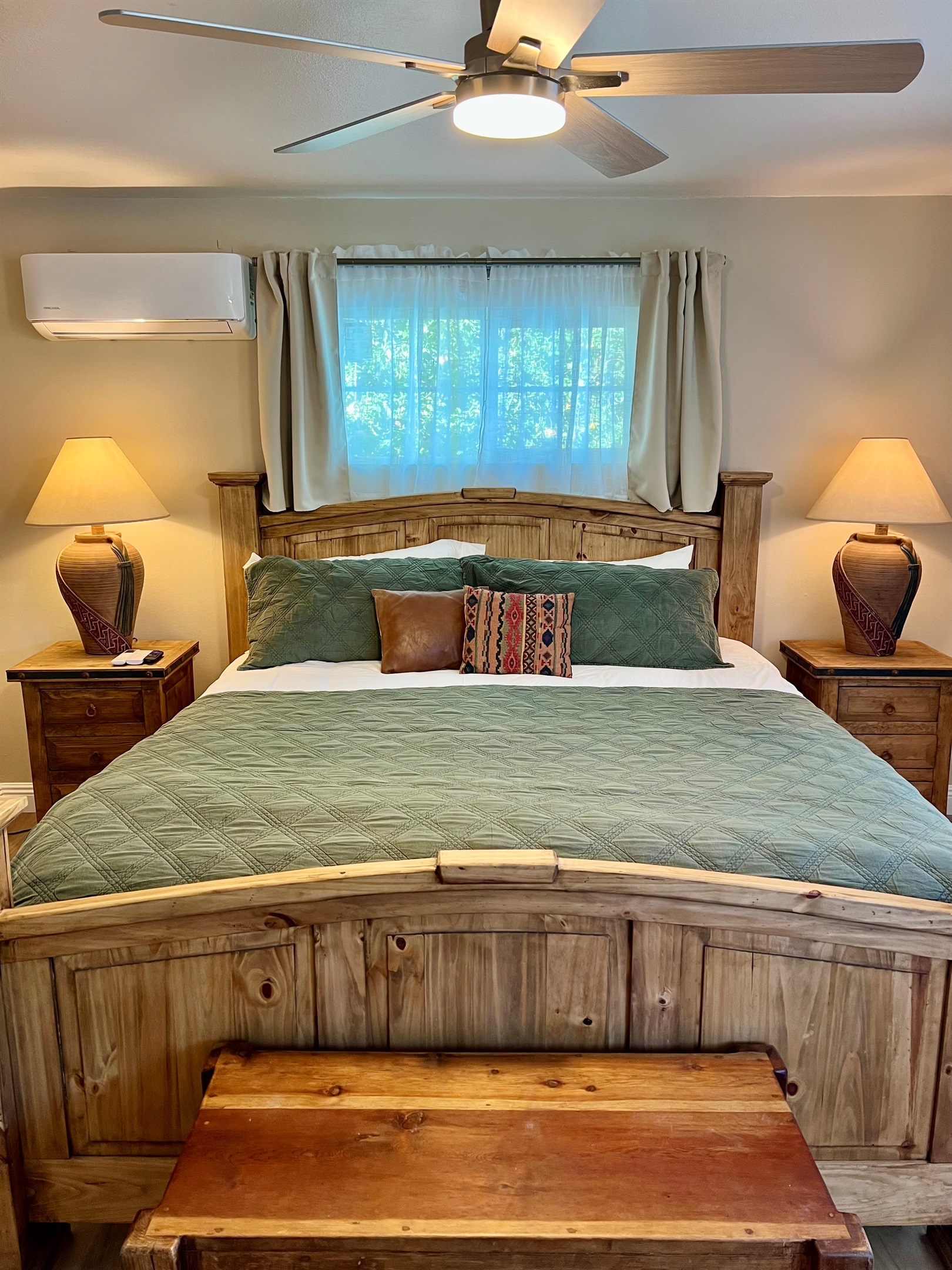Unwind in the spacious bedroom, featuring a plush King-sized bed, a wall-mounted TV, and warm, rustic-style furnishings.