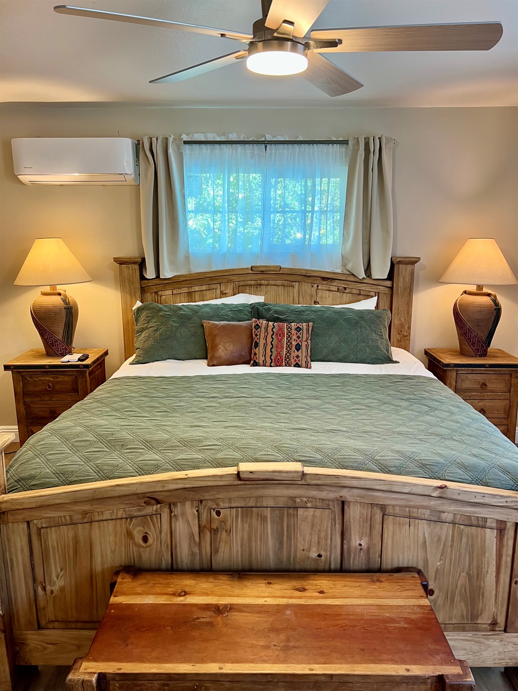 Unwind in the spacious bedroom, featuring a plush King-sized bed, a wall-mounted TV, and warm, rustic-style furnishings.