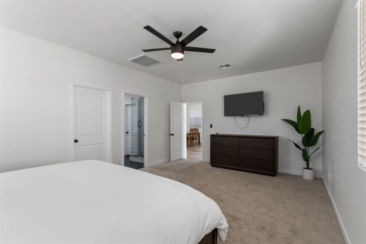 Master bedroom with ensuite bathroom access, large bed, ceiling fan, and a clean, spacious layout for a restful stay.