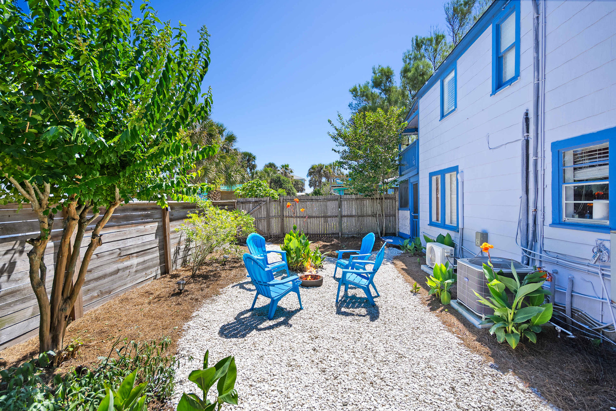 White gravel, bright chairs, and the historic bungalow standing behind. The courtyard is shared with the upstairs unit: usually quiet, and pleasantly sociable on the evenings when you feel like company.