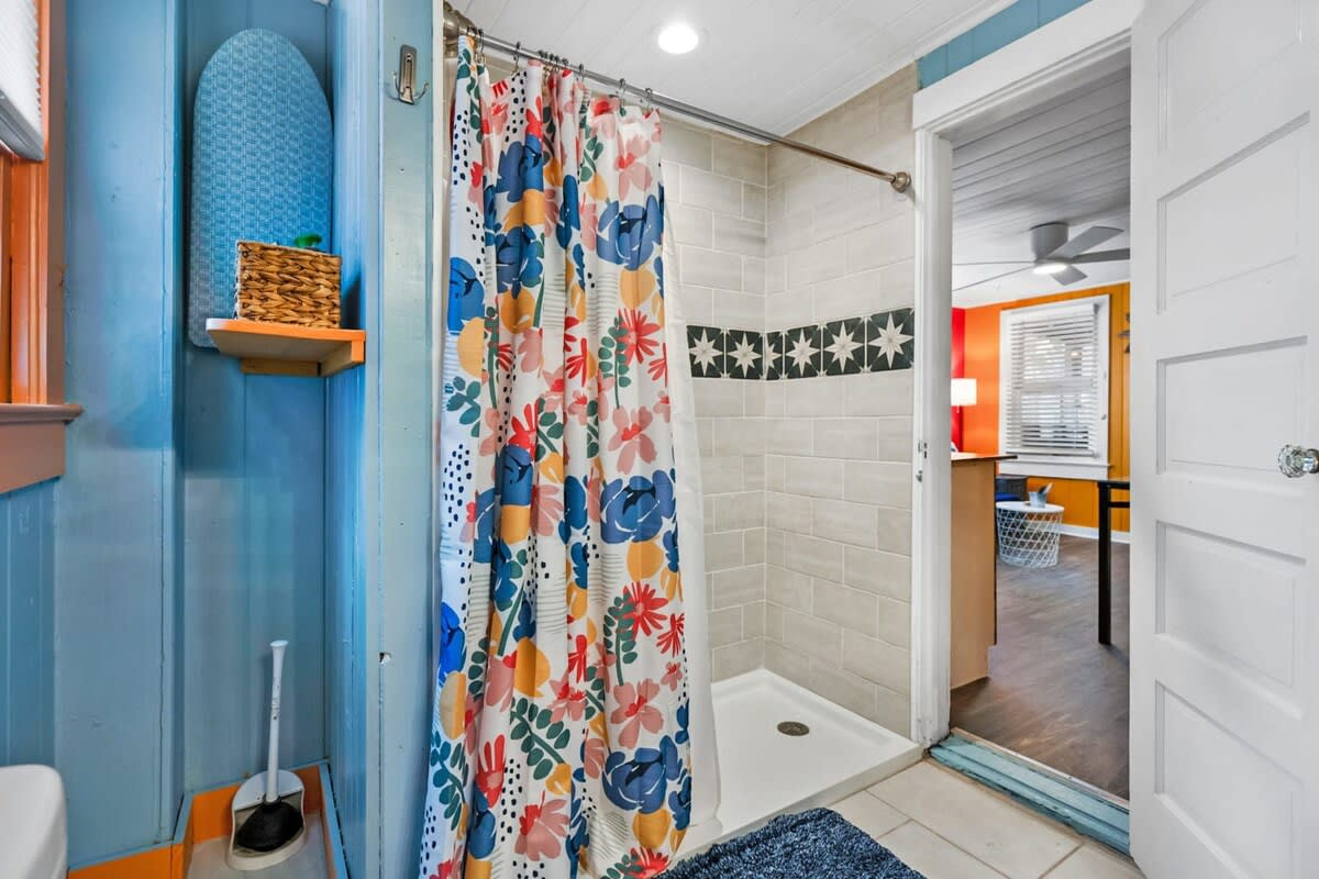 The bathroom sits just off the main living area, with a generous walk-in tiled shower behind the floral curtain. There is no bathtub here, but the shower after a long day in the salt is the real reward.
