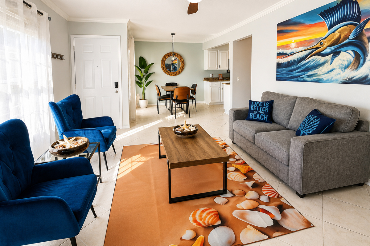 Bright coastal living room with gray sofa, blue armchairs, and sailfish artwork.